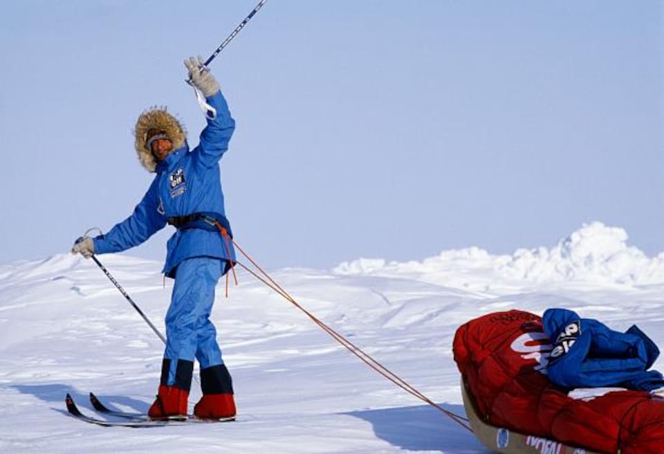 Un homme à ski sur la glace tire un traîneau.