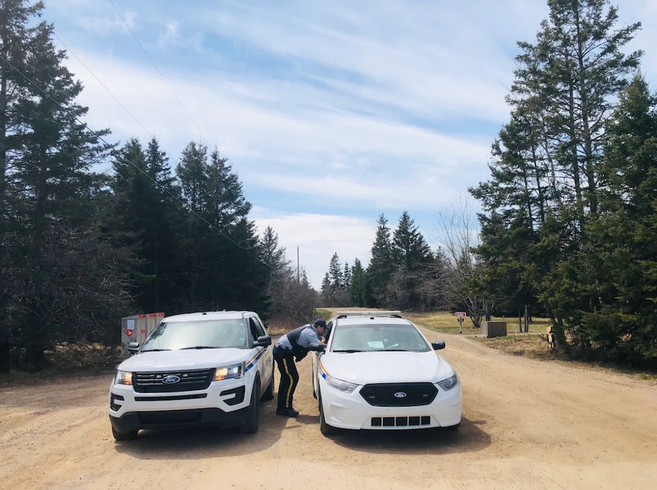 Two Royal Canadian Mounted Police cars are blocking the road. 