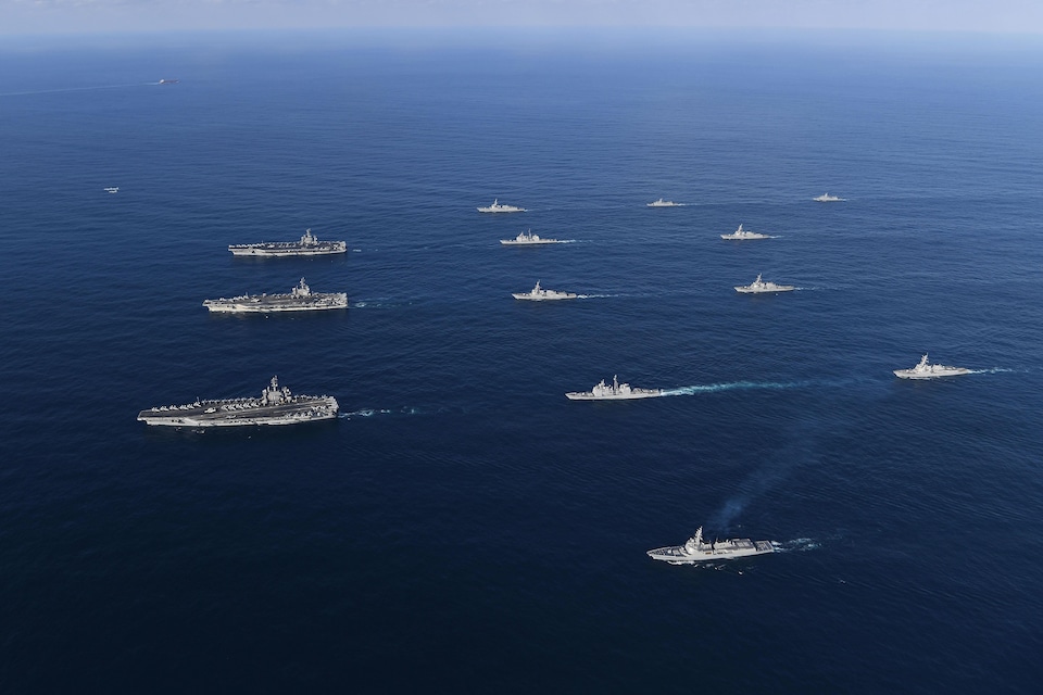 Une flotille américaine composée de trois porte-avions et d'autres bâtiments de guerre vogue sur l'eau. 