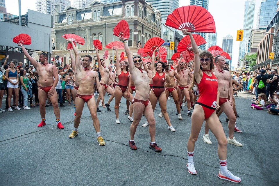 Des personnes vêtues de costumes de bain rouges dansent dans la rue.