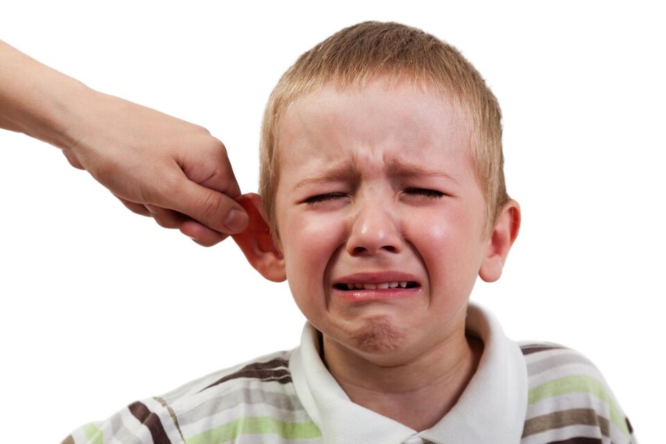Un petit garçon se fait tirer l'oreille par un adulte.