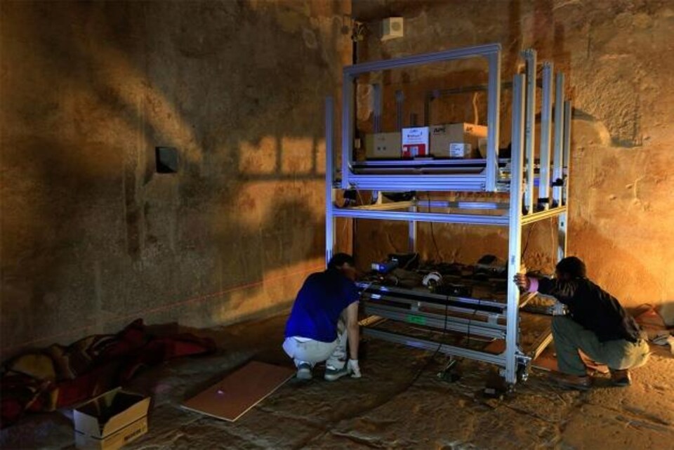 Deux chercheurs ajustent l'appareil servant à détecter les muons circulant à travers la pyramide.