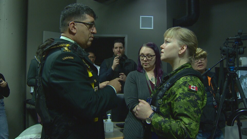 Rakesh Jetly parle à la capitaine, une jeune femme blonde, qui porte un uniforme militaire et un harnais.