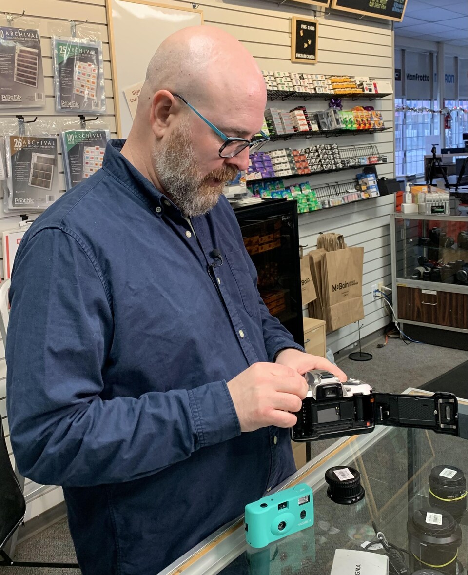 Rene Rodrigue operates a film camera at the McBain Camera store, behind the counter selling negatives.
