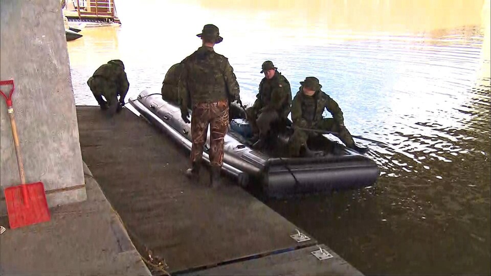 Des militaires prennent place à bord d'un bateau de type Zodiac dans le cadre des opérations d'évacuation du secteur isolé du chemin du Bas-de-la-Rivière à Rigaud, en Montérégie.