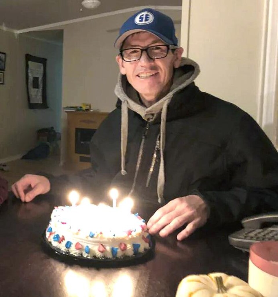 Rodney Levi assis à la table de cuisine, souriant devant un gâteau d'anniversaire.