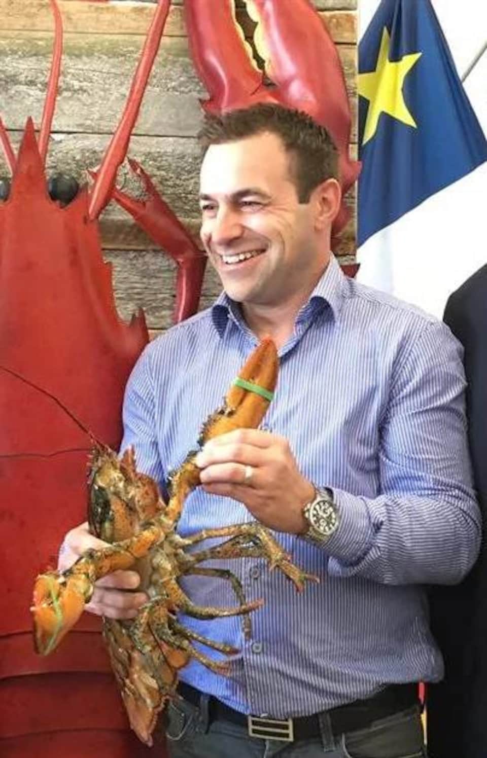 Le ministre provincial Victor Boudreau, Russel Jacob avec un homard dans les mains, et le ministre fédéral Dominic LeBlanc sourient à pleines dents pour une photo de groupe.