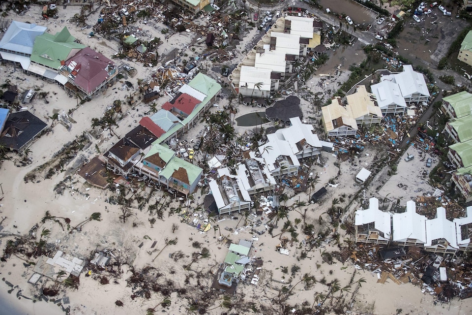 Une plage dévastée de la partie néerlandaise de l'île de Saint-Martin : des bâtiments ont été détruits, et des arbres balayés sur le sable.