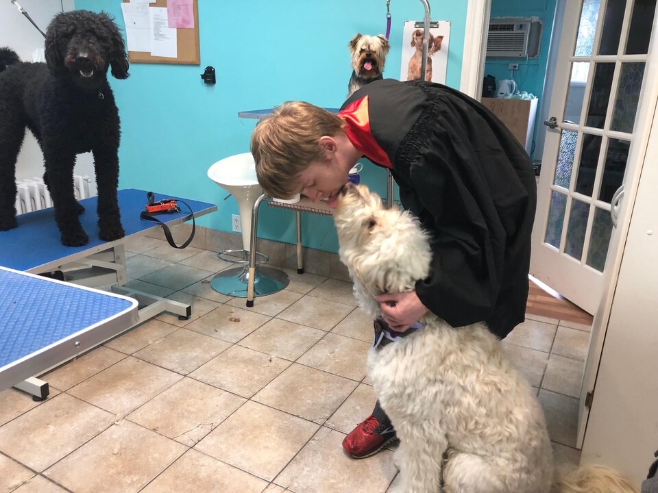 Samuel Ouellet est penché pour embrasser Winter, un grand chien poilu et blanc.