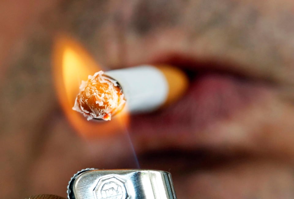 Un homme s'allume une cigarette avec un briquet.