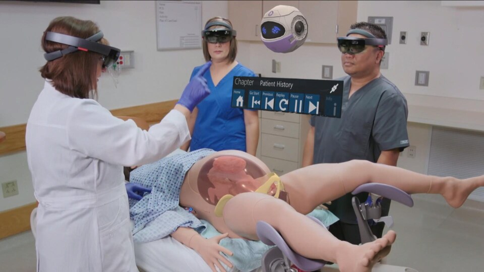 On voit trois professionnels de la santé debout autour d'un mannequin couché sur une table d'opération. Ils utilisent des lunettes de réalité virtuelle.