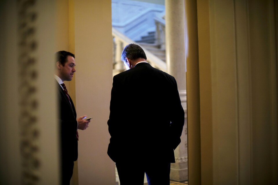 Le sénateur Joe Manchin (à droite) discute avec un attaché politique, en marge du débat sur le projet de réforme fiscale des républicains.