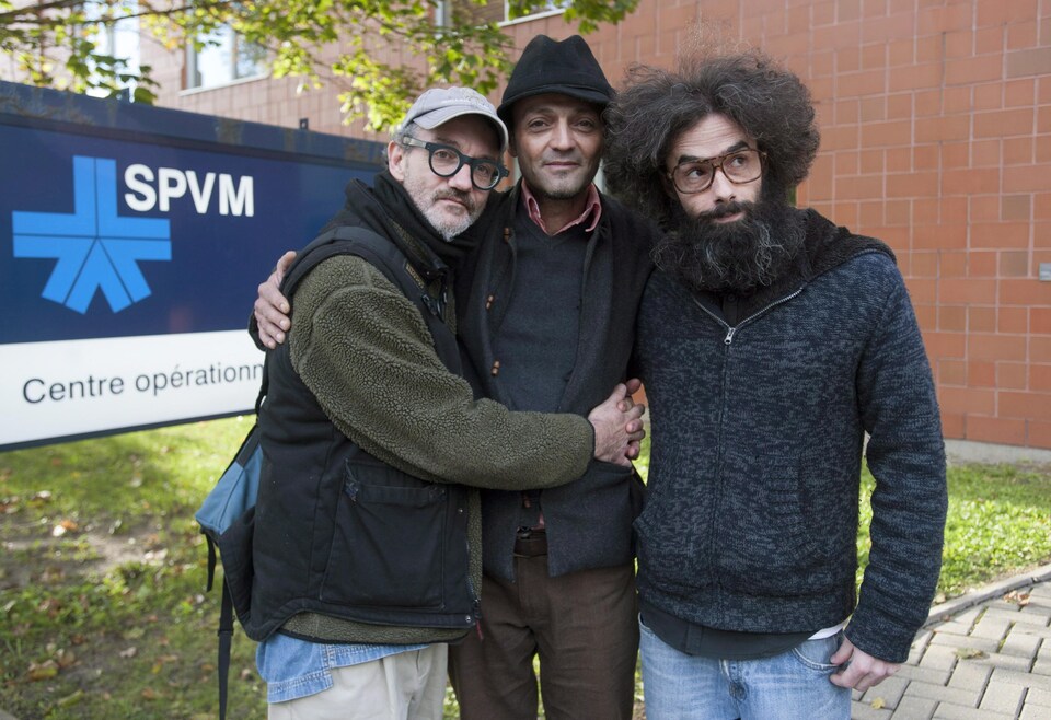Les trois hommes posent devant une enseigne du SPVM.