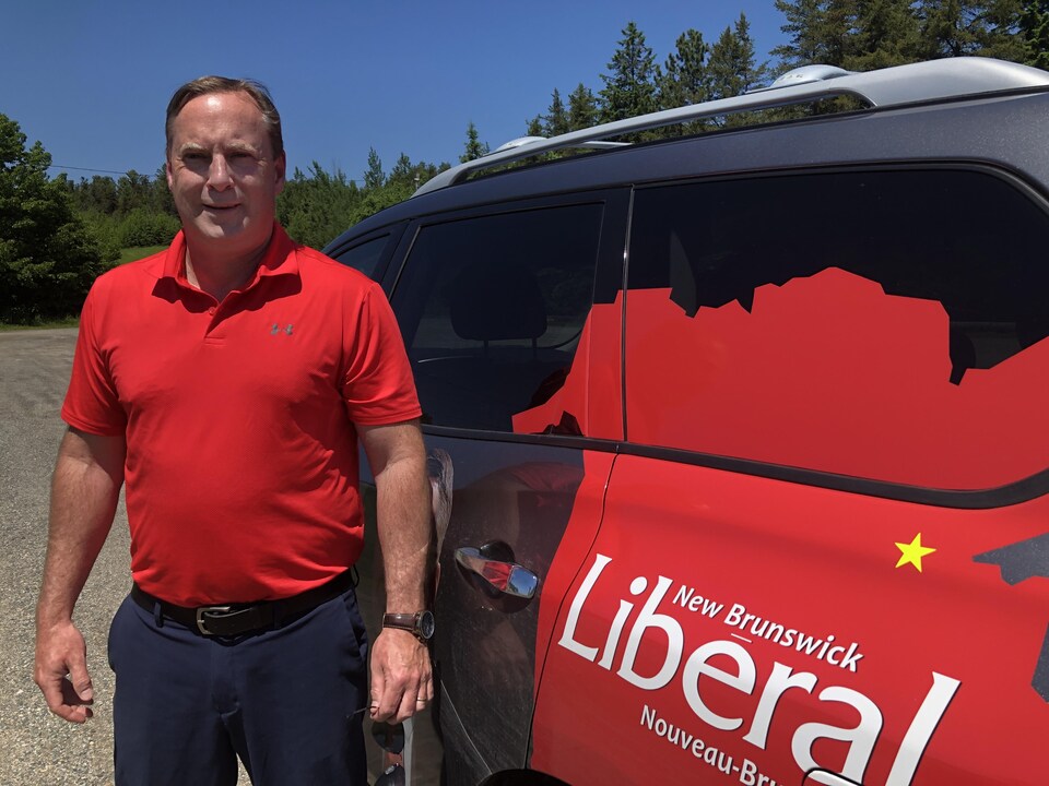 Shawn Wood debout à côté d'un véhicule marqué du logo du Parti libéral.