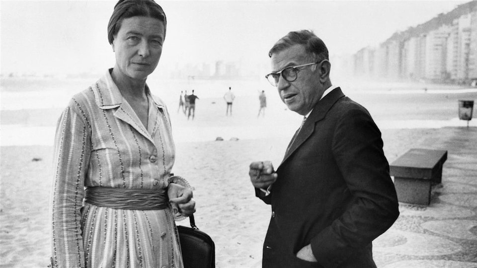 Simone de Beauvoir et Jean-Paul Sartre regardent l'objectif en se retournant alors qu'il sont sur la plage de Copacabana, à Rio, en 1960.