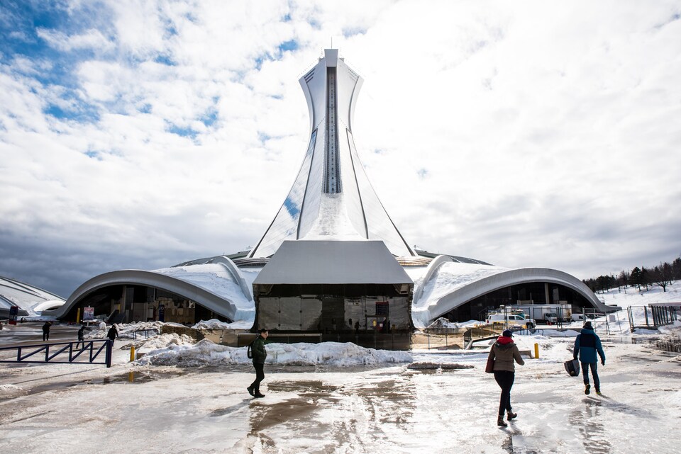 Des gens marchent à l'arrière du Stade olympique de Montréal.