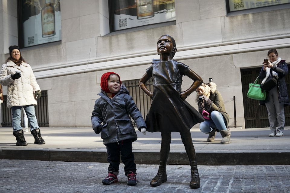 A little girl poses next to the statue.