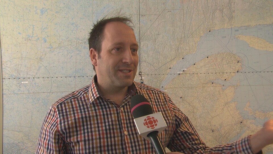 Un homme en entrevue à Radio-Canada devant une carte du Québec.
