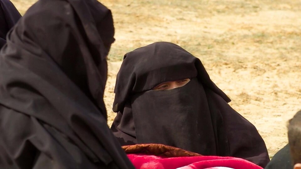 Deux femmes vêtues de burqas sont assises sur le sol.