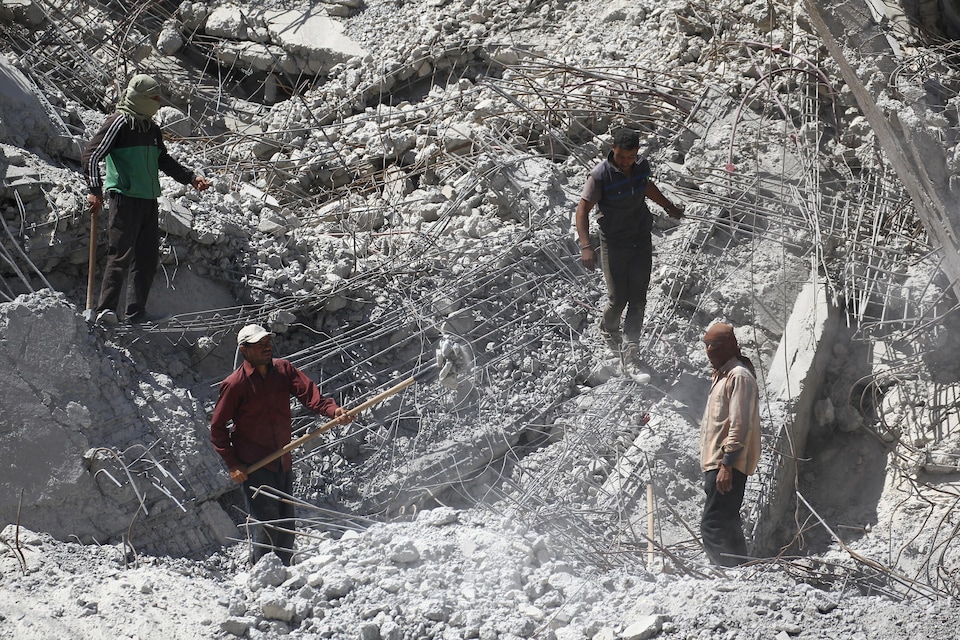 Des travailleurs creusent le sol à travers les ruines à Raqa le 18 avril 2018. 