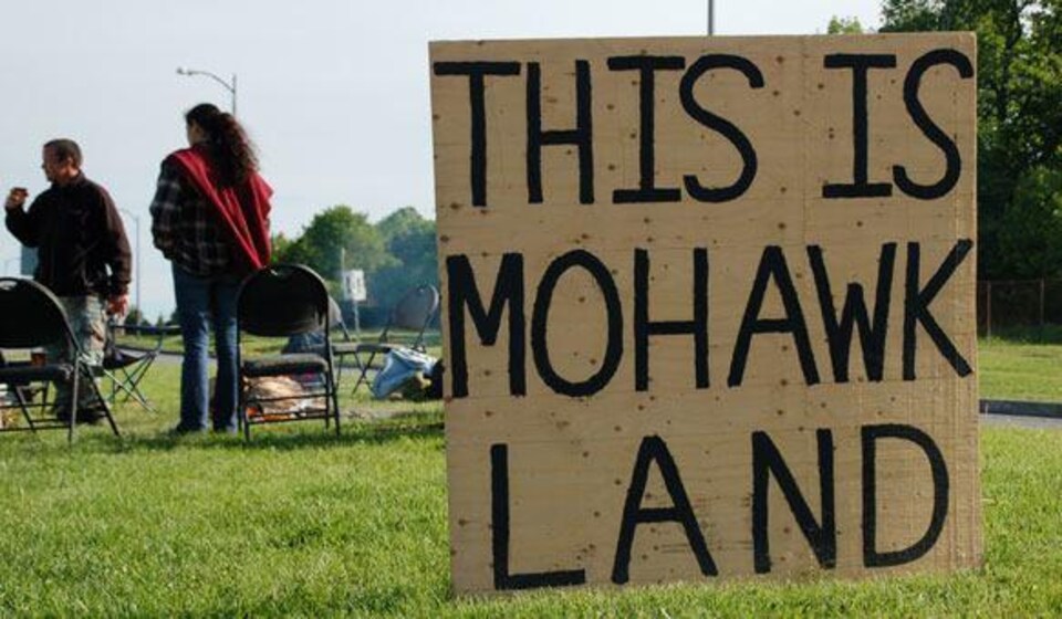 Un panneau « This is mohawk land » planté sur un terrain. 
