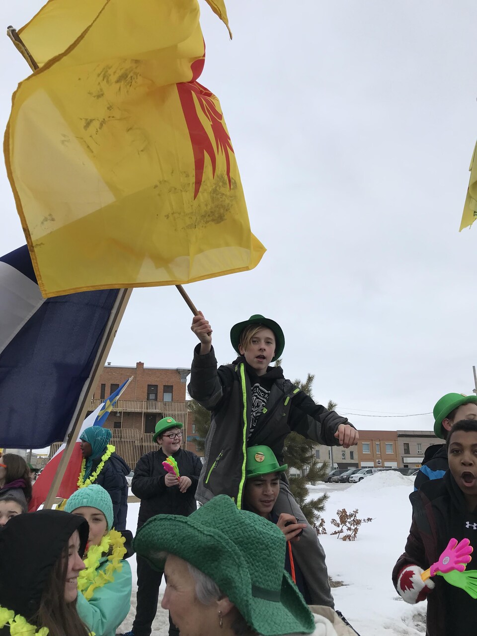 Un garçon brandit le drapeau fransaskois lors du défilé.