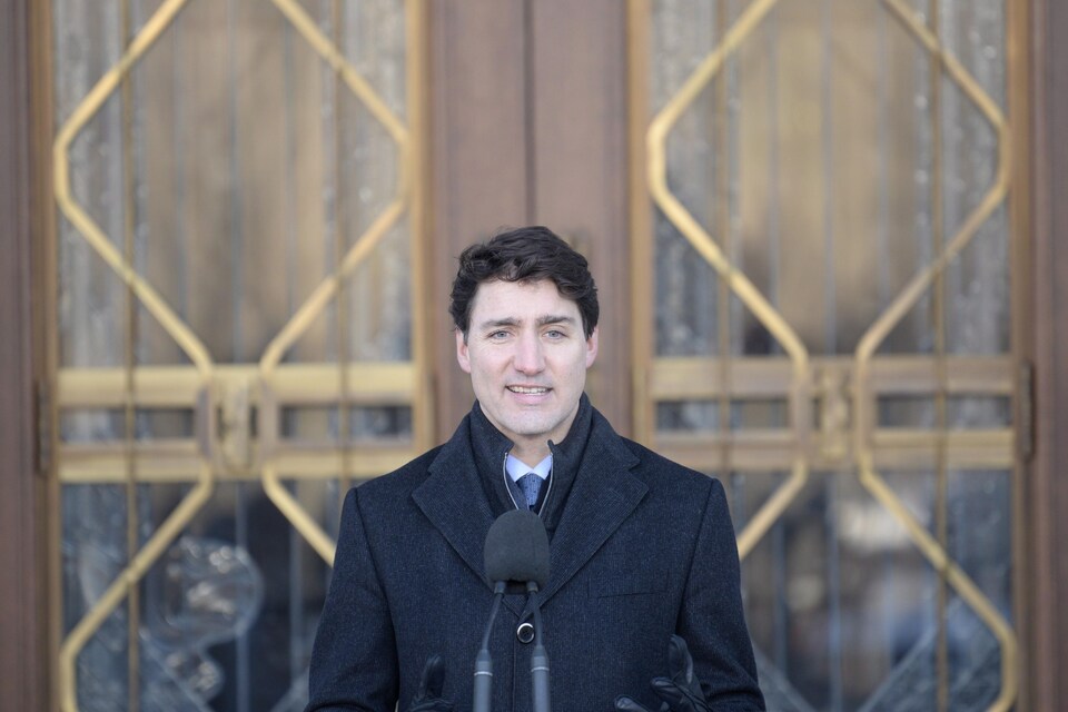 Justin Trudeau en tenue hivernale devant un microphone.