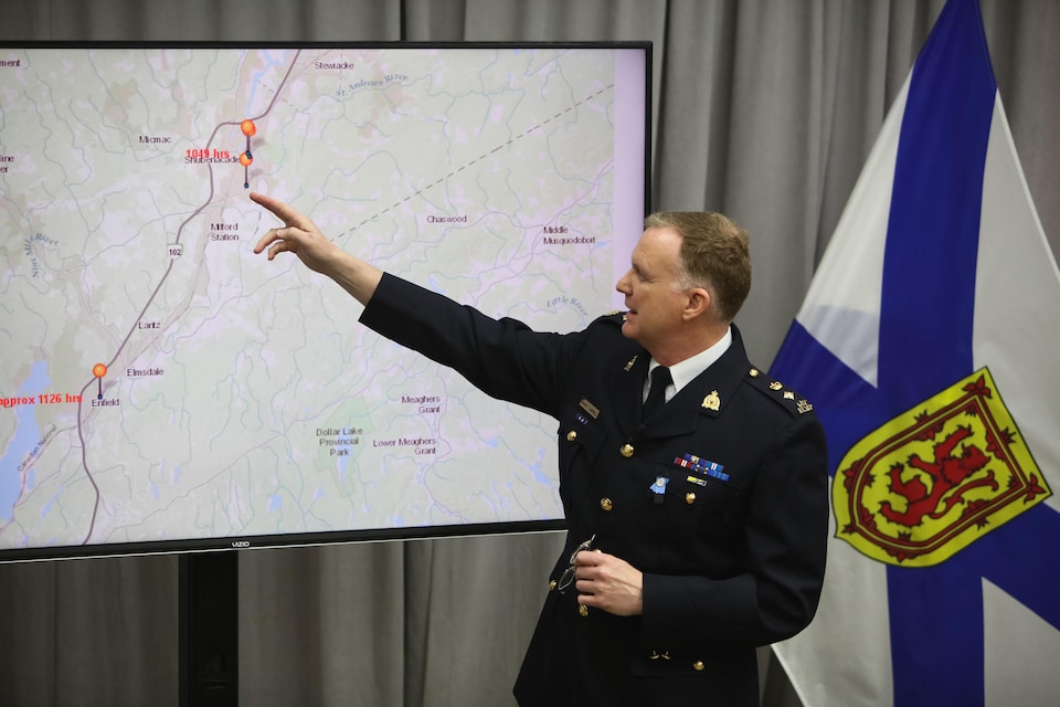 Un homme en uniforme de policier montre un écran sur lequel apparaissent une carte routière et des indications de trajet parcouru.