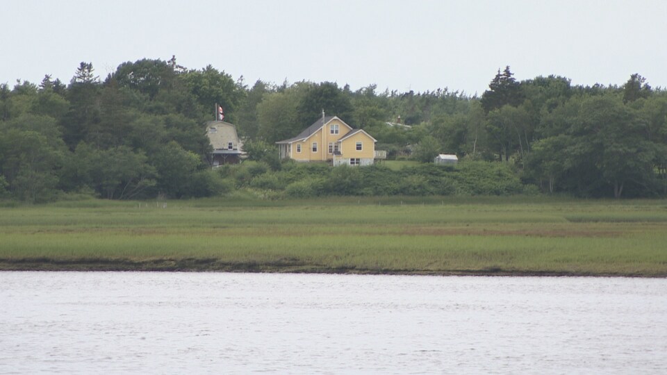 Une maison avec les drapeaux de l'Acadie et du Canada.
