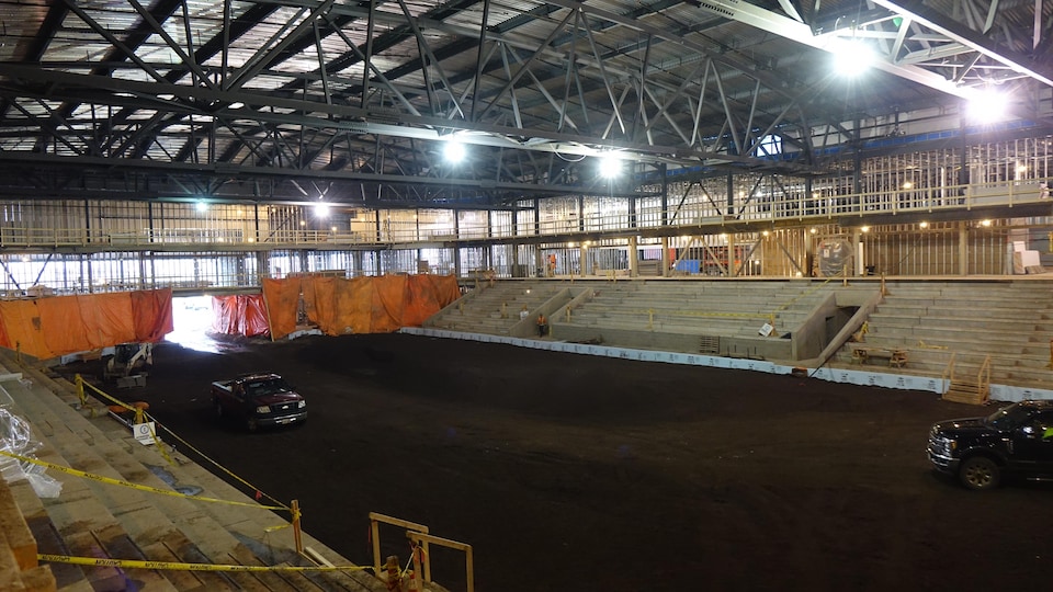 A large rectangle of land surrounded by concrete bleachers covered with a metal roof. 