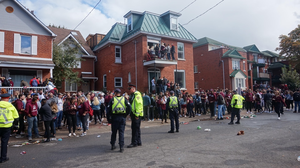 Quelques policiers dispersés dans une rue surveillent des jeunes qui font la fête sur le trottoir à Ottawa.