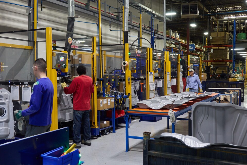 Des ouvriers qui utilisent des machines, dans l'usine Spectra Premium de Boucherville.