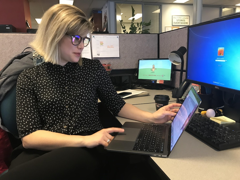 Une femme blonde aux lunettes travaille sur un ordinateur portable sur un bureau