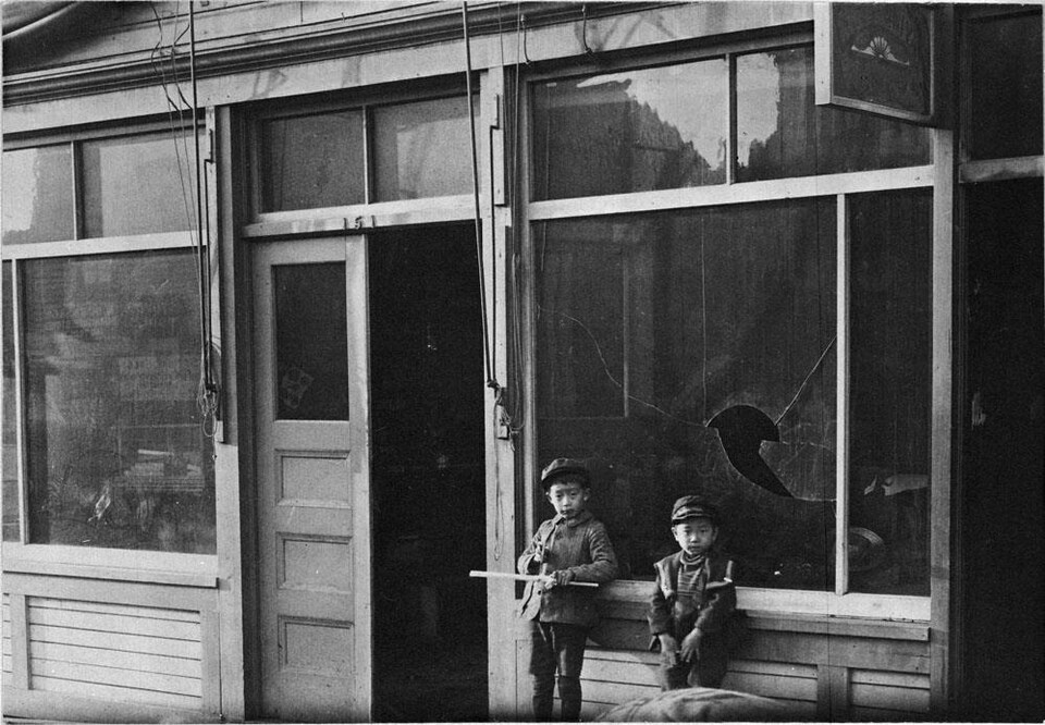 Deux enfants aux traits asiatiques devant une vitrine fracassée