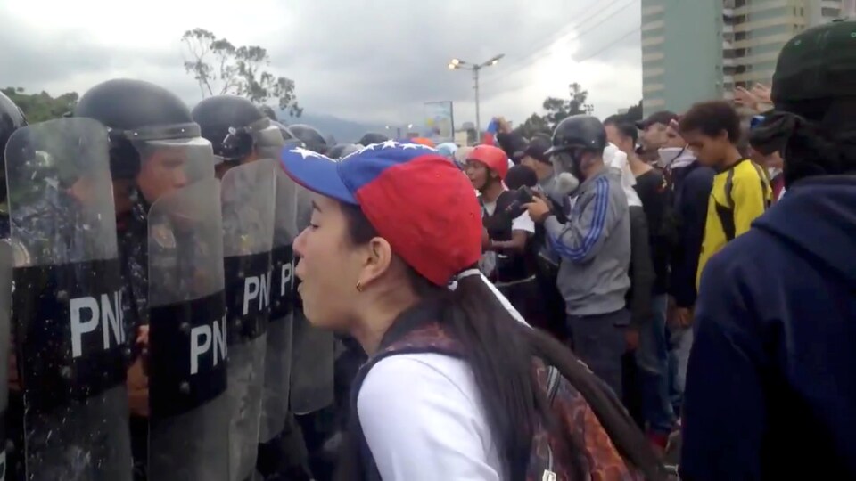 Des personnes participent à une manifestation alors que la police monte la garde à Caracas au Venezuela, le 23 janvier 2019.