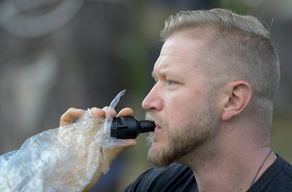 Un homme fume de la marijuana à l'aide d'un masque vapoteur