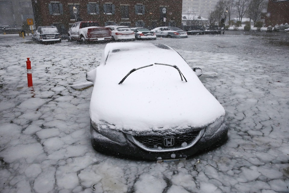 A car parked in a flooded street near Boston Harbor on Thursday.