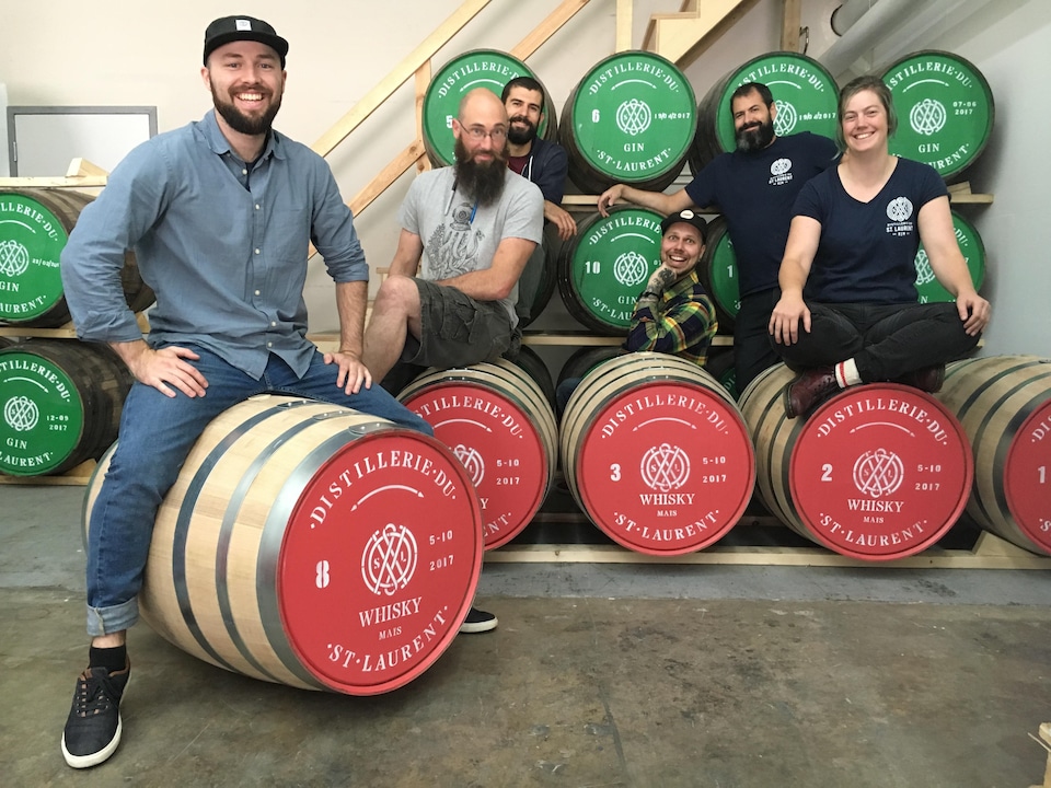 Joël Pelletier, copropriétaire de la Distillerie du St. Laurent, et toute son équipe sont fièrement assis sur leurs nouveaux barils de whisky.