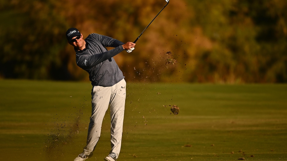 Le golfeur termine son élan et regarde la balle au loin.