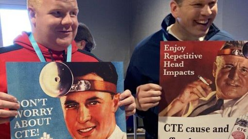 Deux hommes tiennent des affiches.