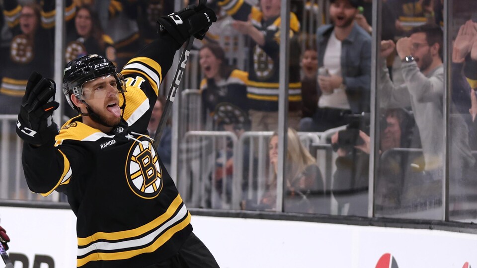 Un hockeyeur sort la langue et lève les bras.