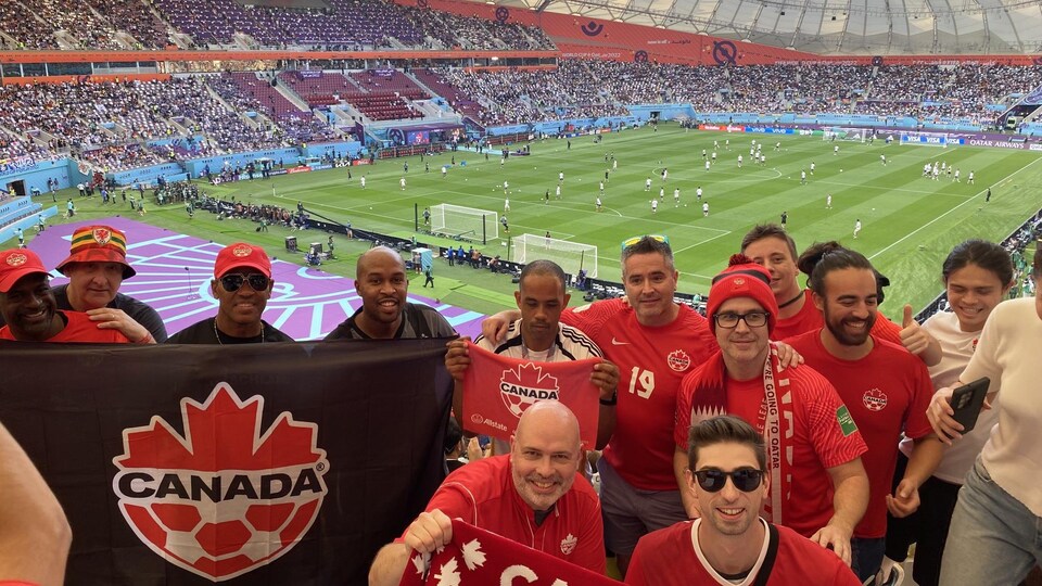 Des partisans de soccer prennent une photo avec le drapeau du Canada.