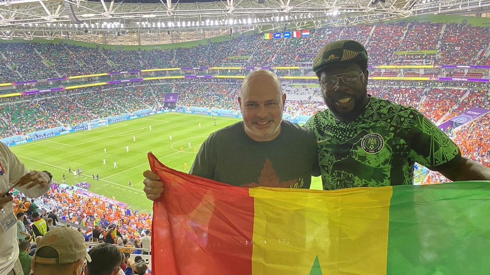 Deux partisans de soccer prennent une photo dans un stade avec le drapeau du Sénégal.