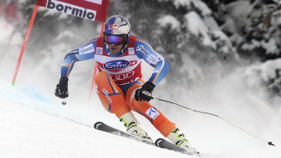 Le skieur, concentré, négocie un virage.