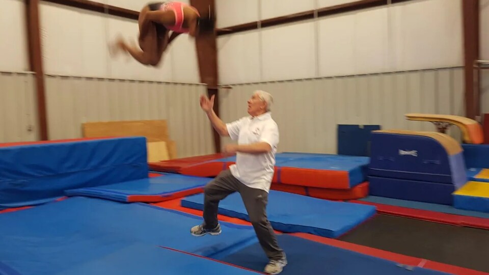 Alex Bard en train d'aider une gymnaste à faire une manoeuvre.