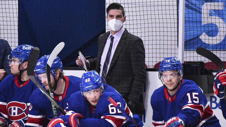 Il regarde l'action derrière le banc du Canadien de Montréal, où se trouvent quatre joueurs.