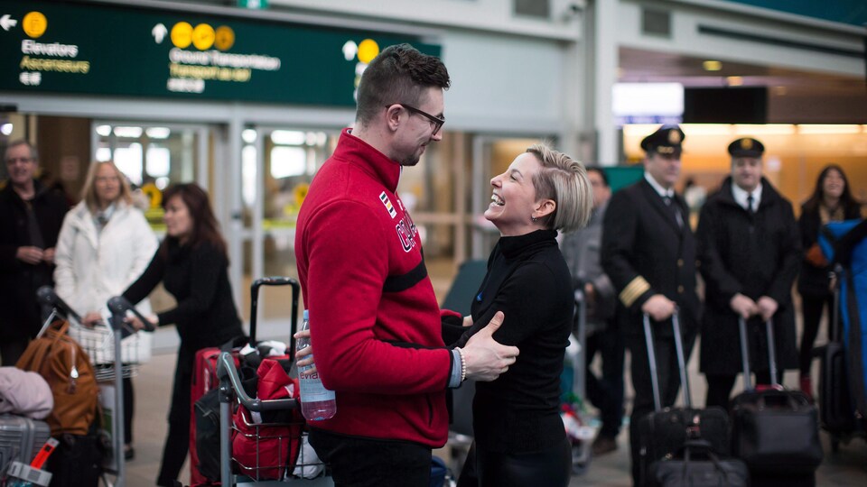 Un homme et une femme s'étreignent à l'aéroport.