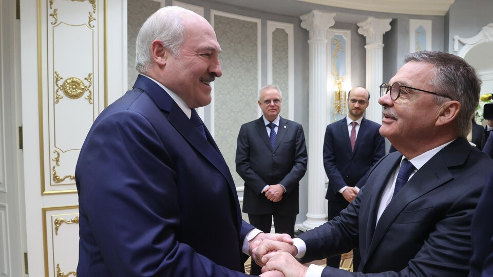 Deux hommes en veston se serrent les mains chaleureusement.