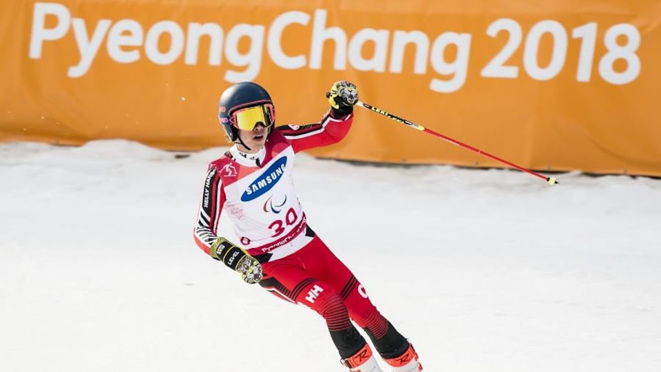 Un skieur freine à l'arrivée devant une bannière de Pyeongchang 2018.