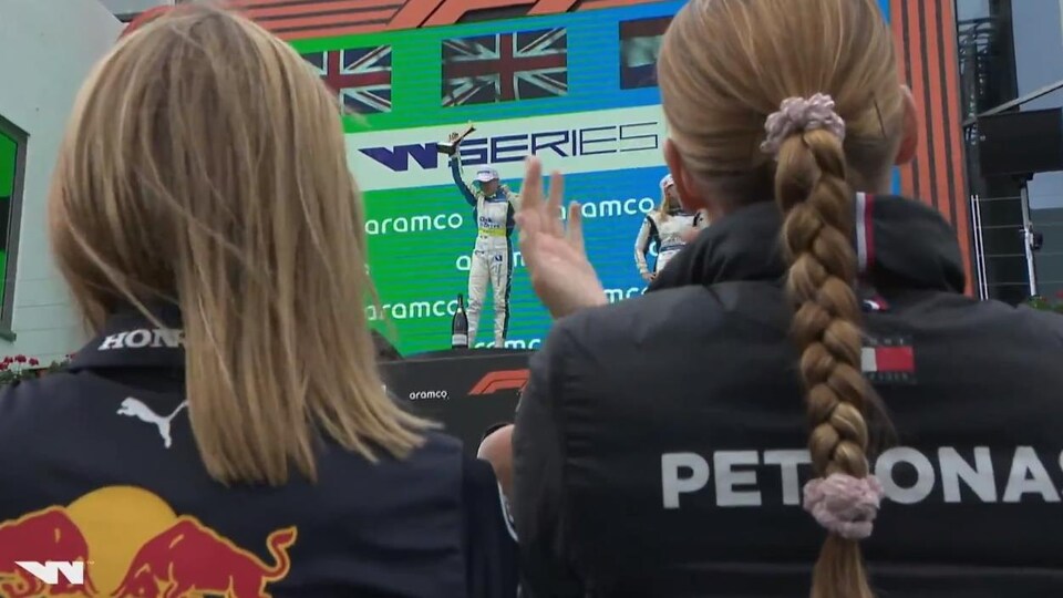 Deux femmes regardent la gagnante de la course sur le podium.